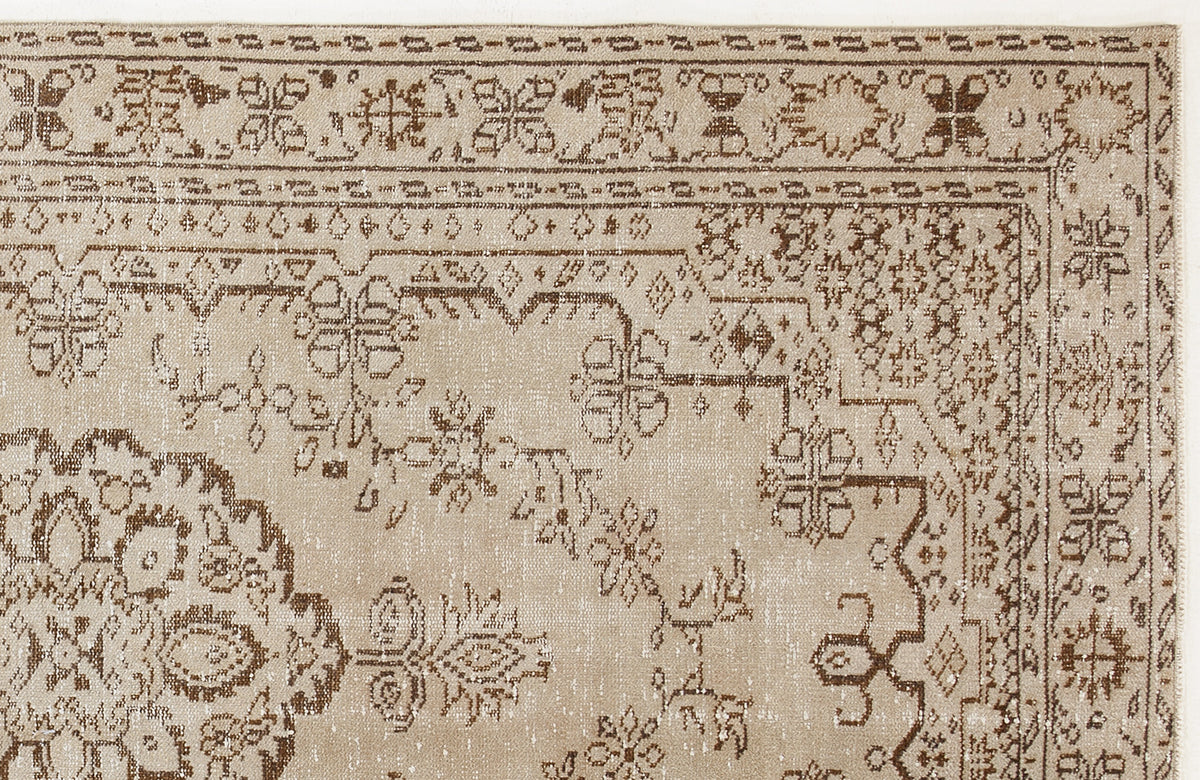 Beige and brown traditional rug with a distressed floral medallion pattern and ornate geometric border.