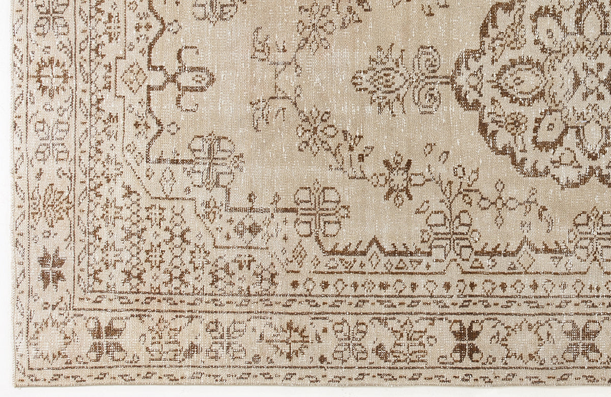 Beige and brown rug with a distressed traditional medallion and floral border pattern.