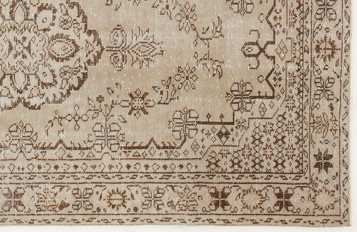 Beige and brown distressed rug with a traditional floral medallion and geometric border pattern.