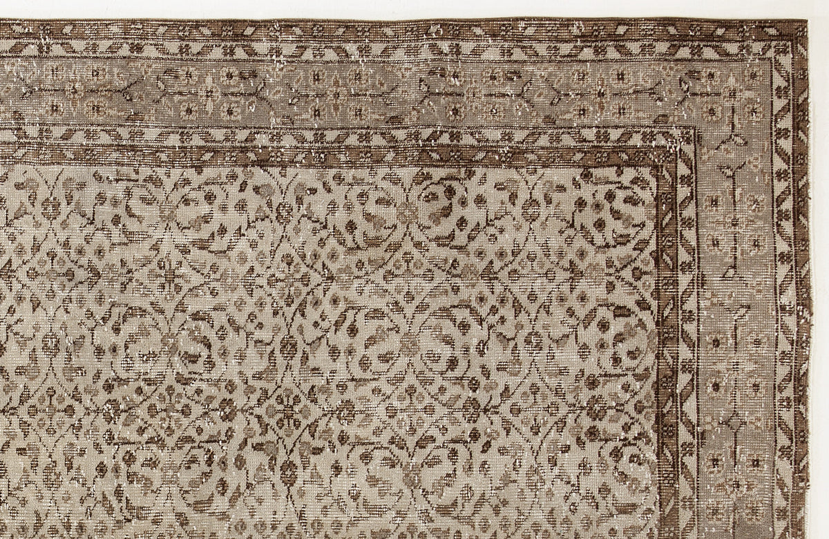 Taupe and brown vintage-style rug with a distressed floral vine pattern and a geometric border.
