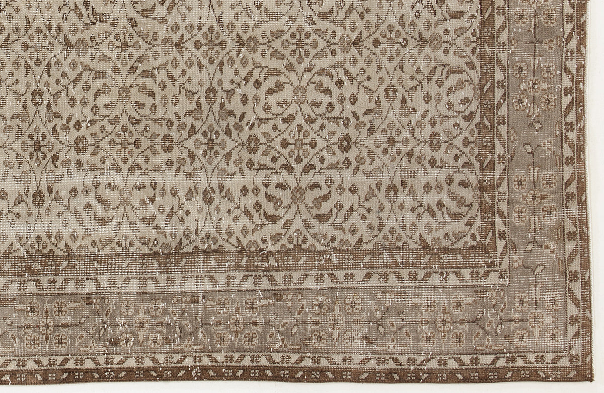 Taupe and brown distressed rug with a traditional floral medallion pattern and a decorative border.