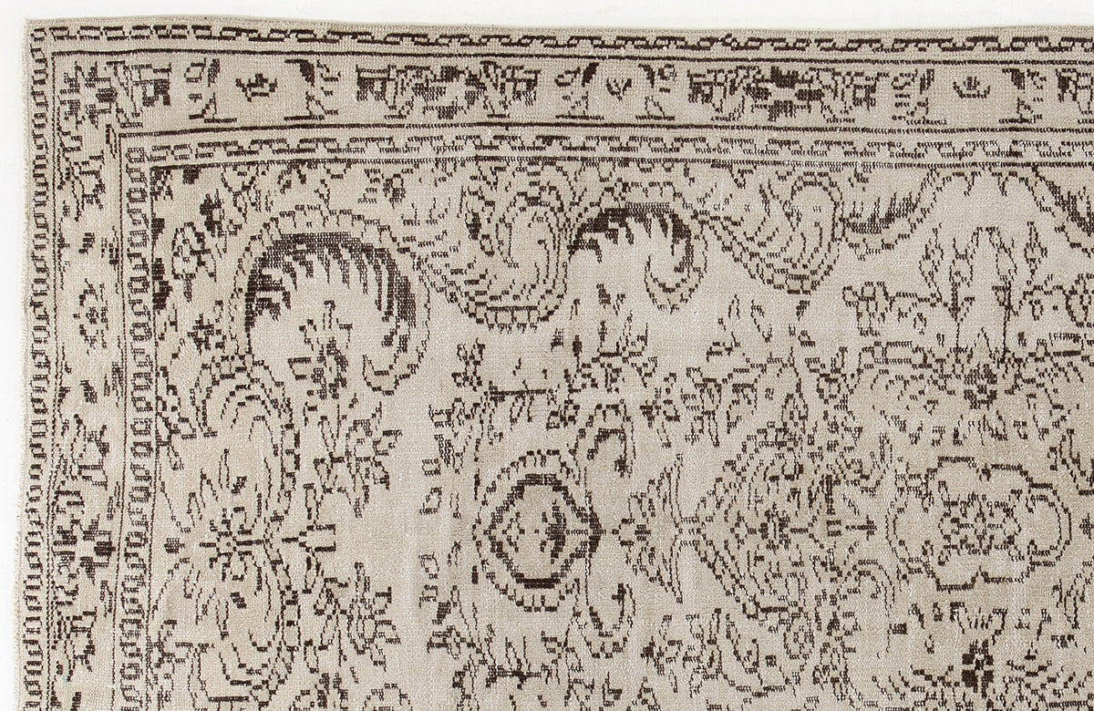 Beige rug with a dark brown distressed traditional floral pattern and a geometric border.