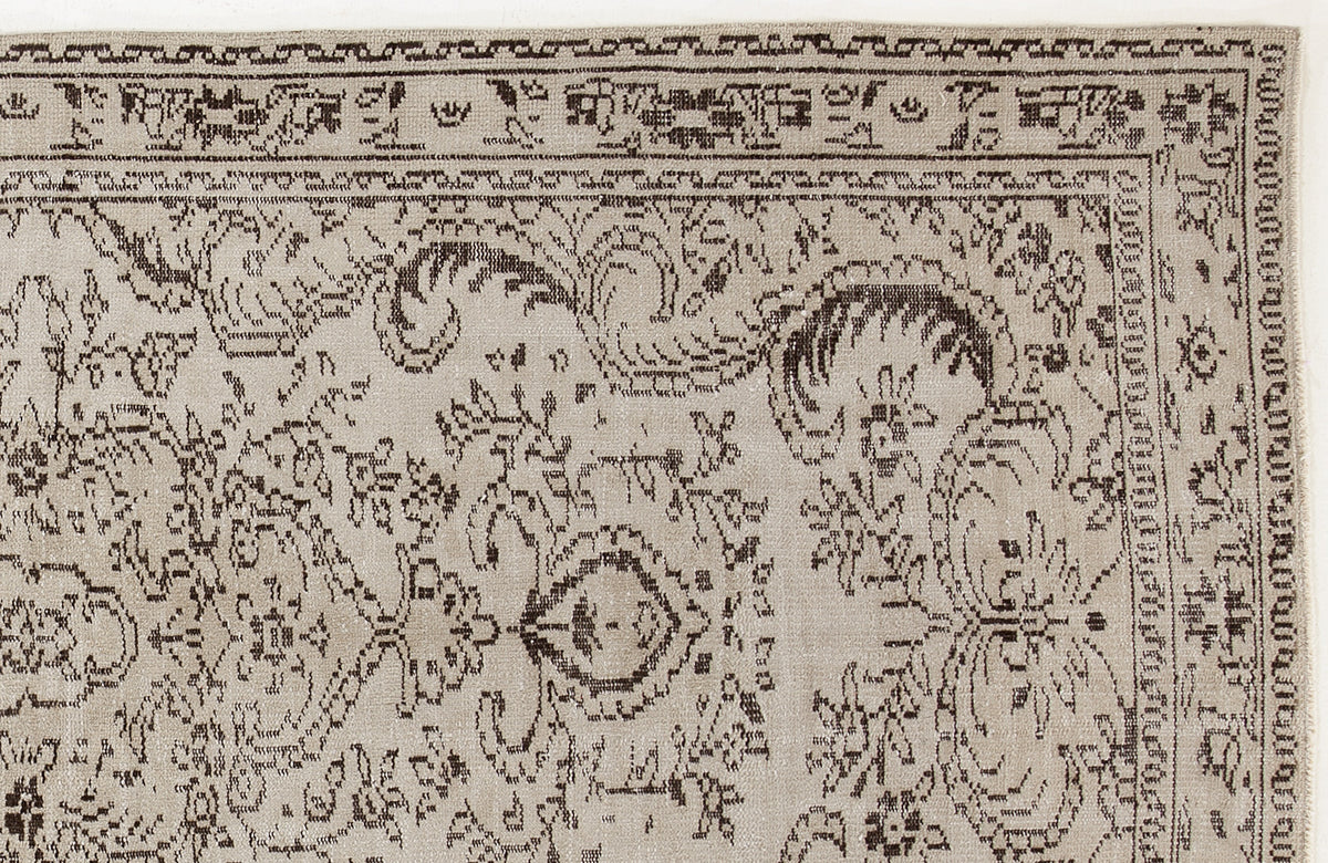 Beige rug with a dark brown traditional floral medallion pattern and a geometric border.