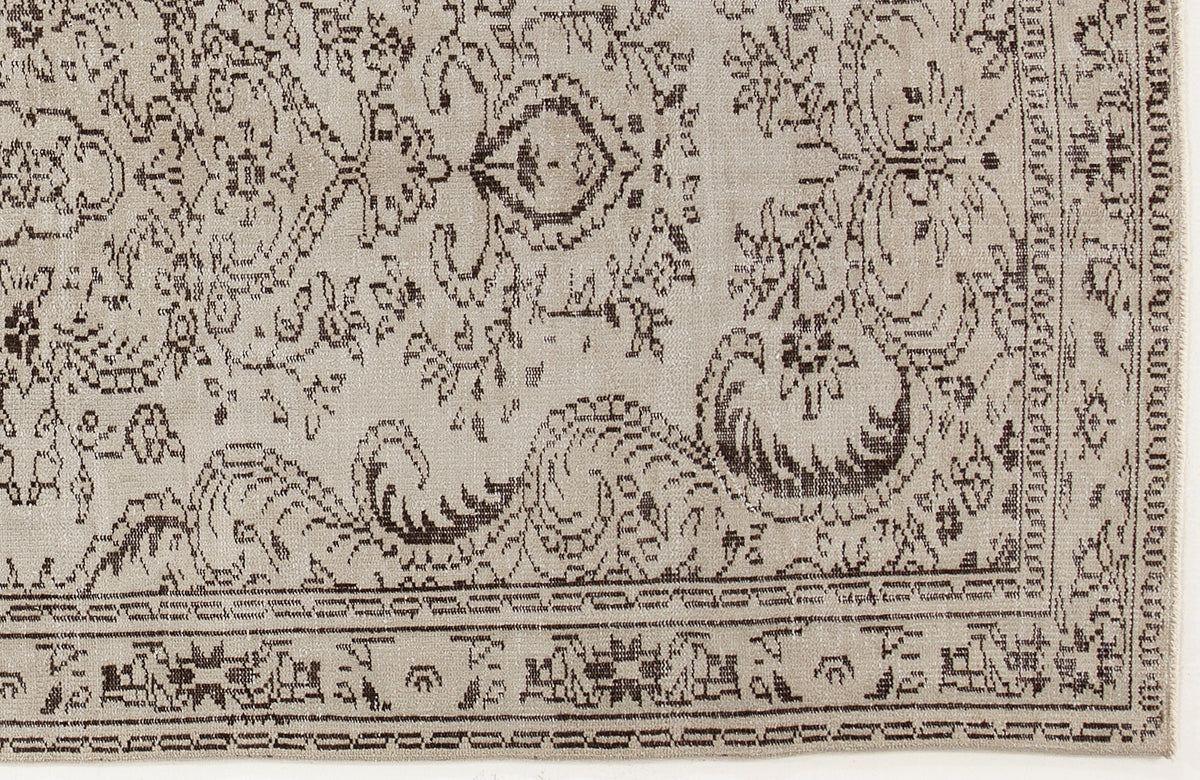 Beige rug with a dark brown traditional floral medallion pattern and a detailed geometric border.