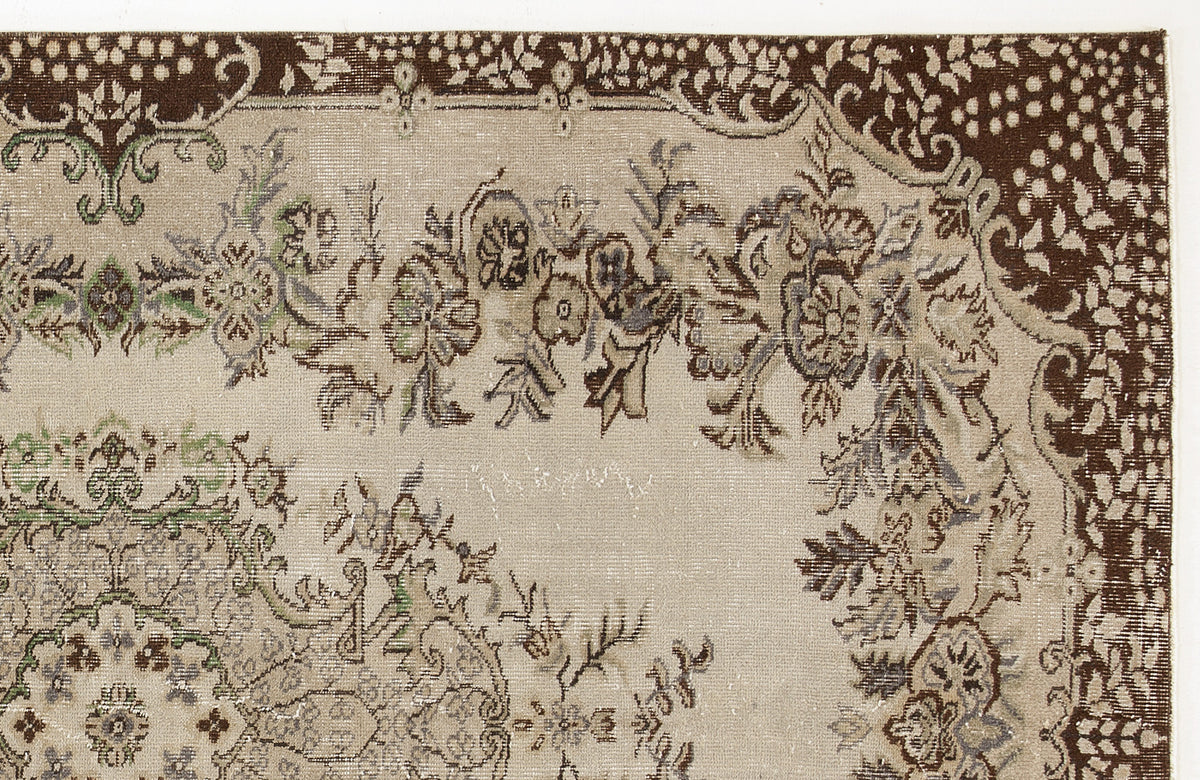 Beige rug with a dark brown floral border and intricate, distressed botanical patterns in green, grey, and brown.
