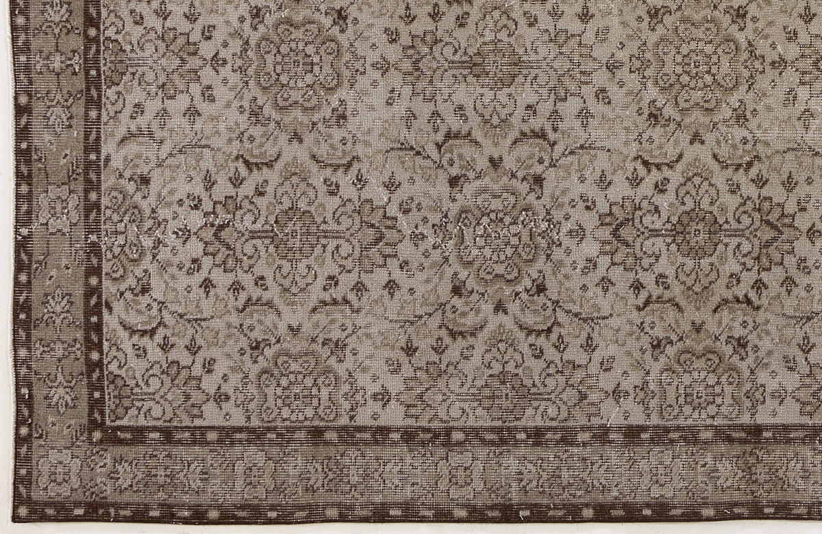Taupe and dark brown rug with a distressed traditional floral medallion pattern and a decorative border.
