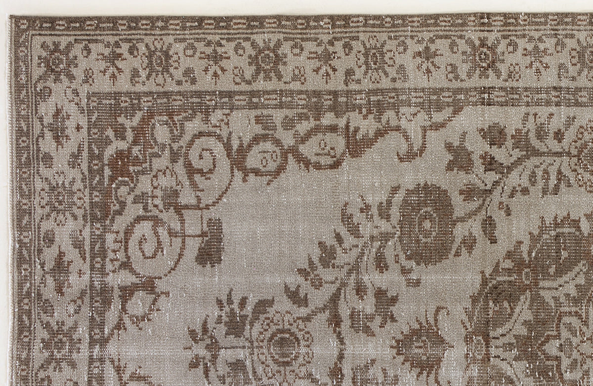 Taupe and brown distressed rug with a traditional floral medallion border and intricate botanical motifs.