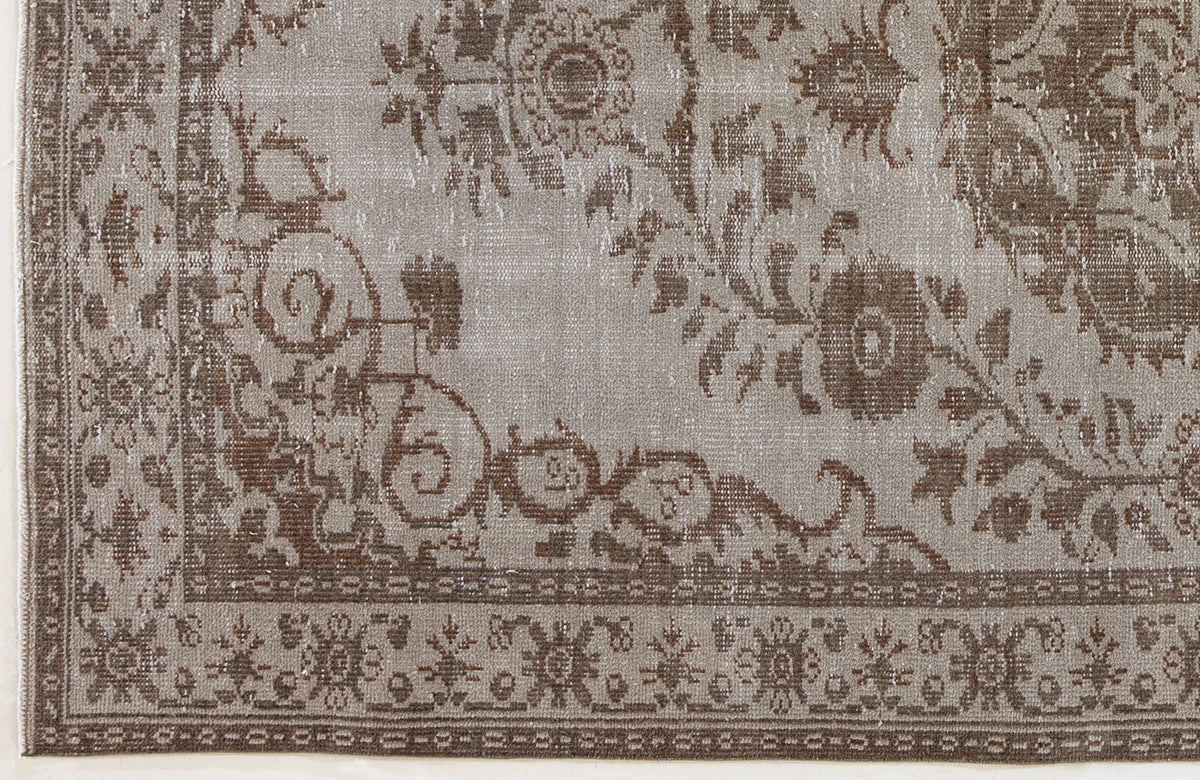 Taupe and brown distressed rug with a traditional floral medallion pattern and a detailed geometric border.