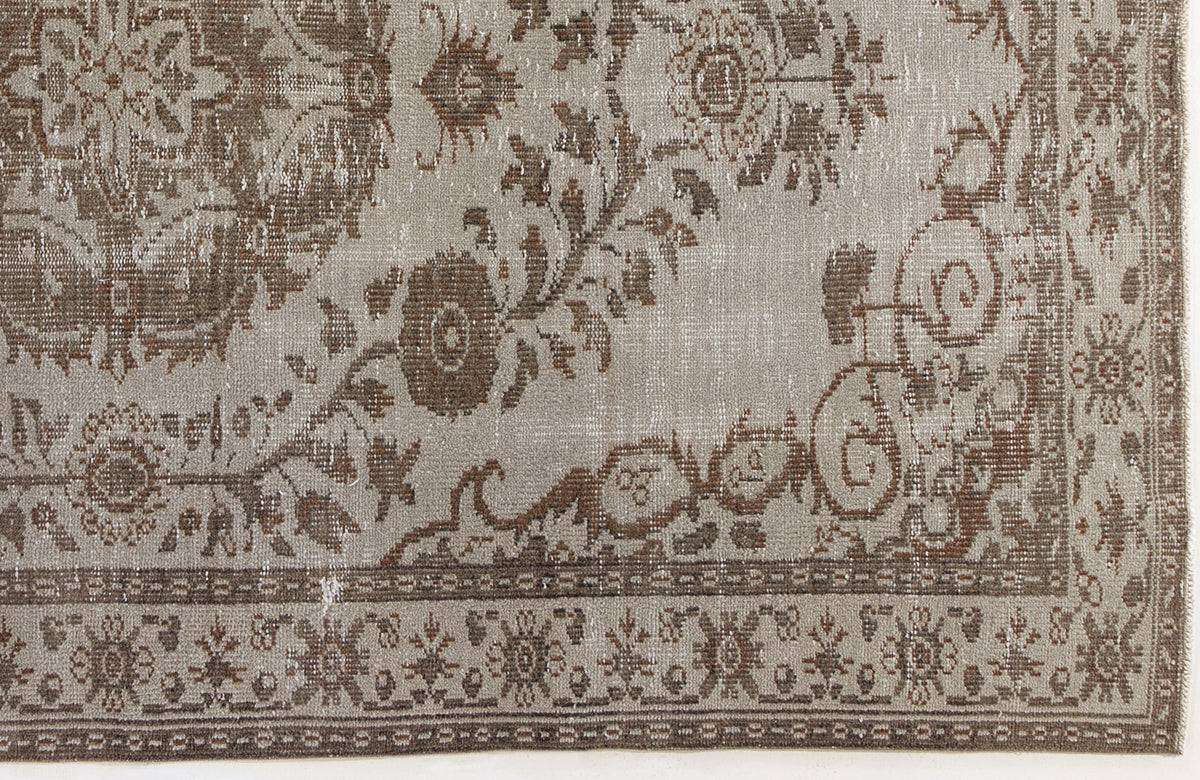Taupe and brown distressed rug with a traditional floral medallion pattern and a decorative border.