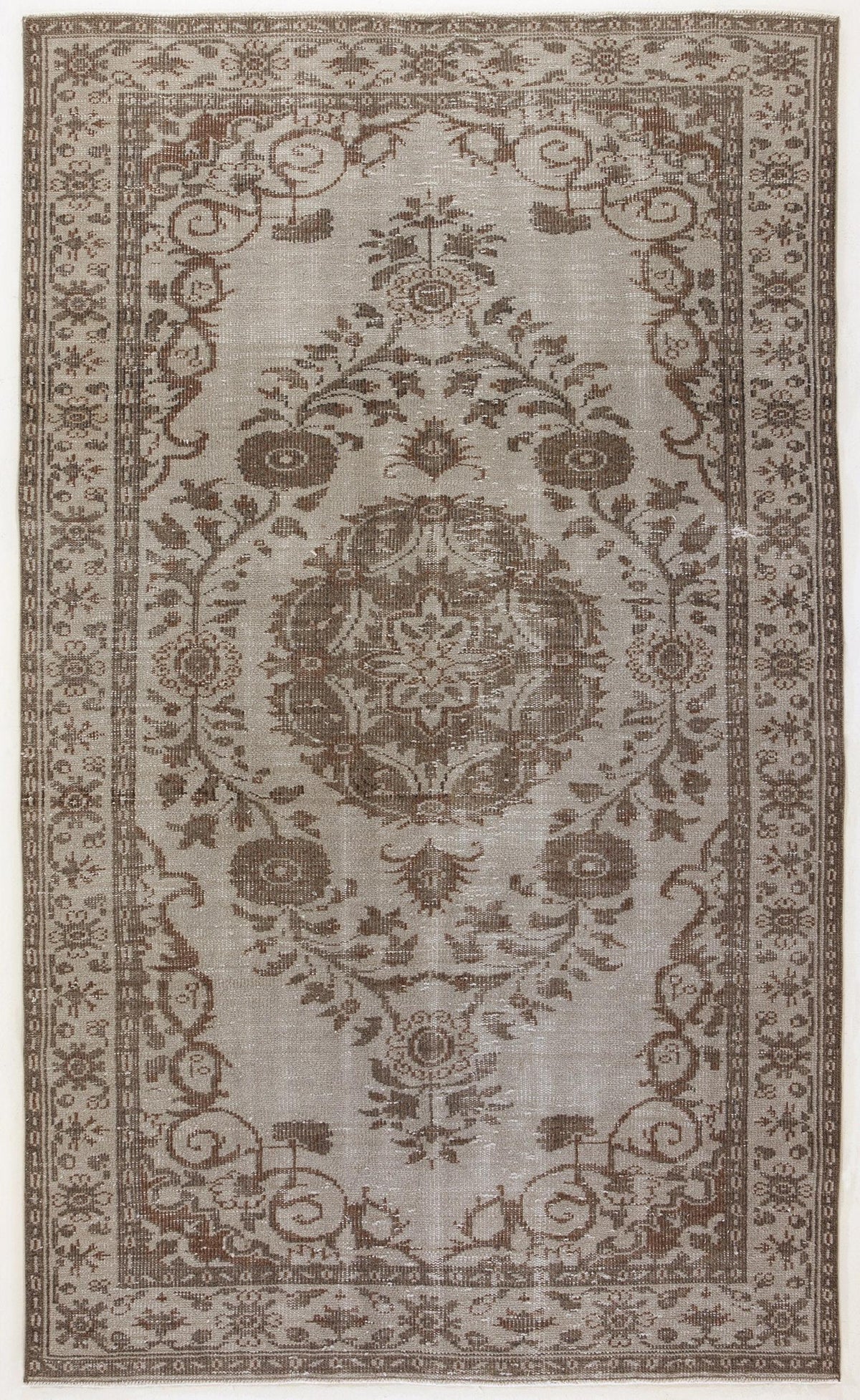 Taupe and brown distressed rug with a central floral medallion and ornate botanical border.