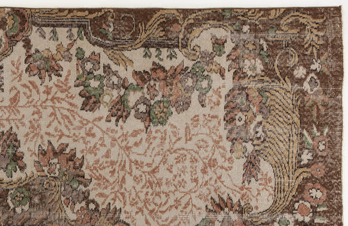 Load image 1 in gallery view. Distressed beige rug with a brown border and intricate floral and vine patterns in muted green, rust, and brown tones.