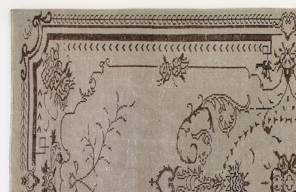 Taupe rug with a dark brown traditional border and intricate floral line-work pattern on a white background.
