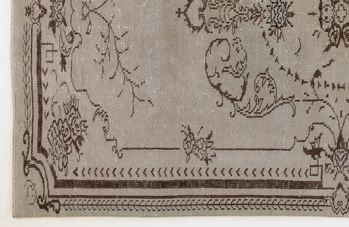 Taupe rug with a distressed dark brown traditional floral border and central medallion pattern.