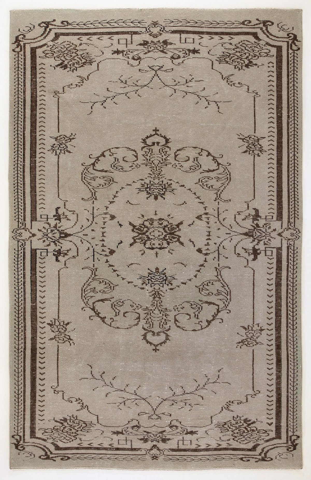 Taupe and dark brown area rug featuring a central floral medallion and ornate border on a white background.