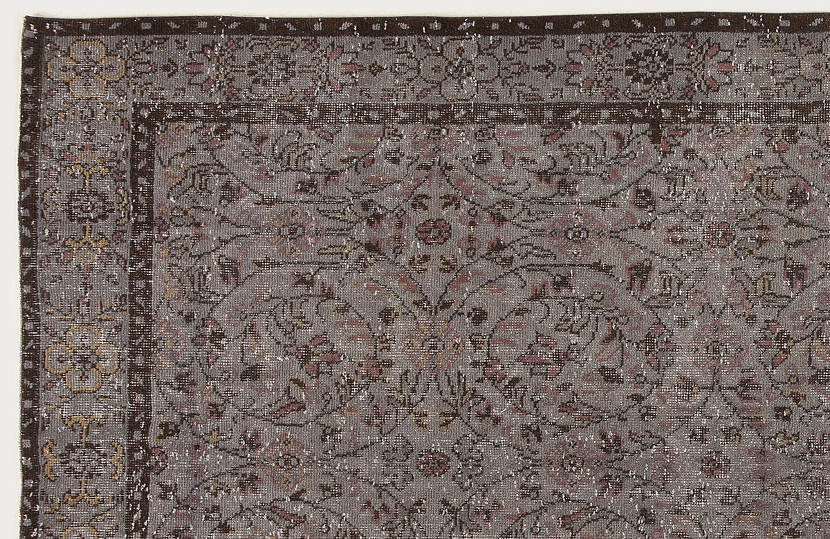 Grey and brown traditional rug with a distressed floral medallion pattern and a dark border.