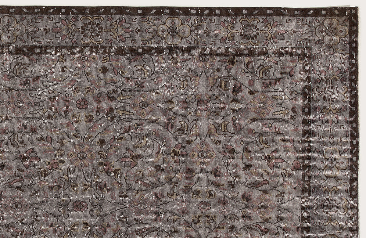 Grey and brown traditional rug with a distressed floral medallion pattern and a dark border.