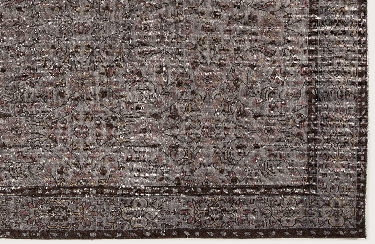 Grey and brown distressed rug with a traditional floral medallion pattern and a detailed border.