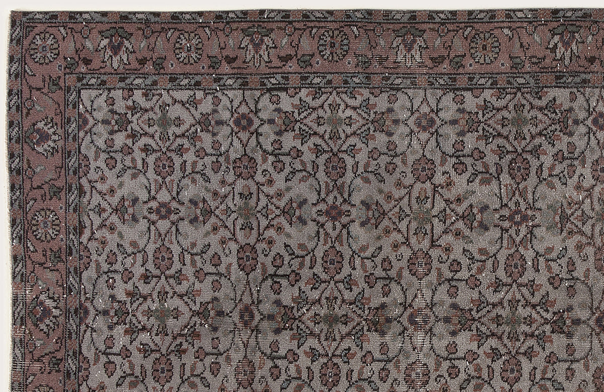 Muted mauve and grey traditional rug with a dense floral vine pattern and a decorative border.