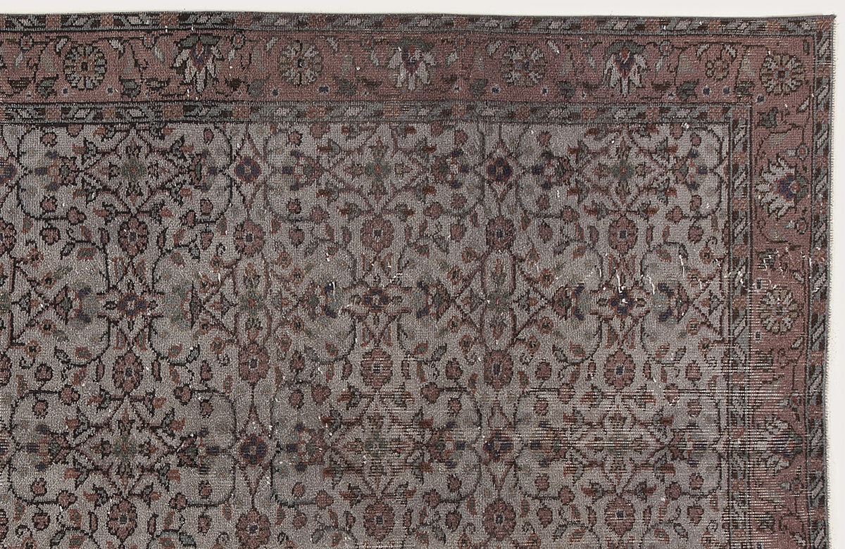Muted mauve and grey traditional rug with a distressed floral vine pattern and a decorative border.