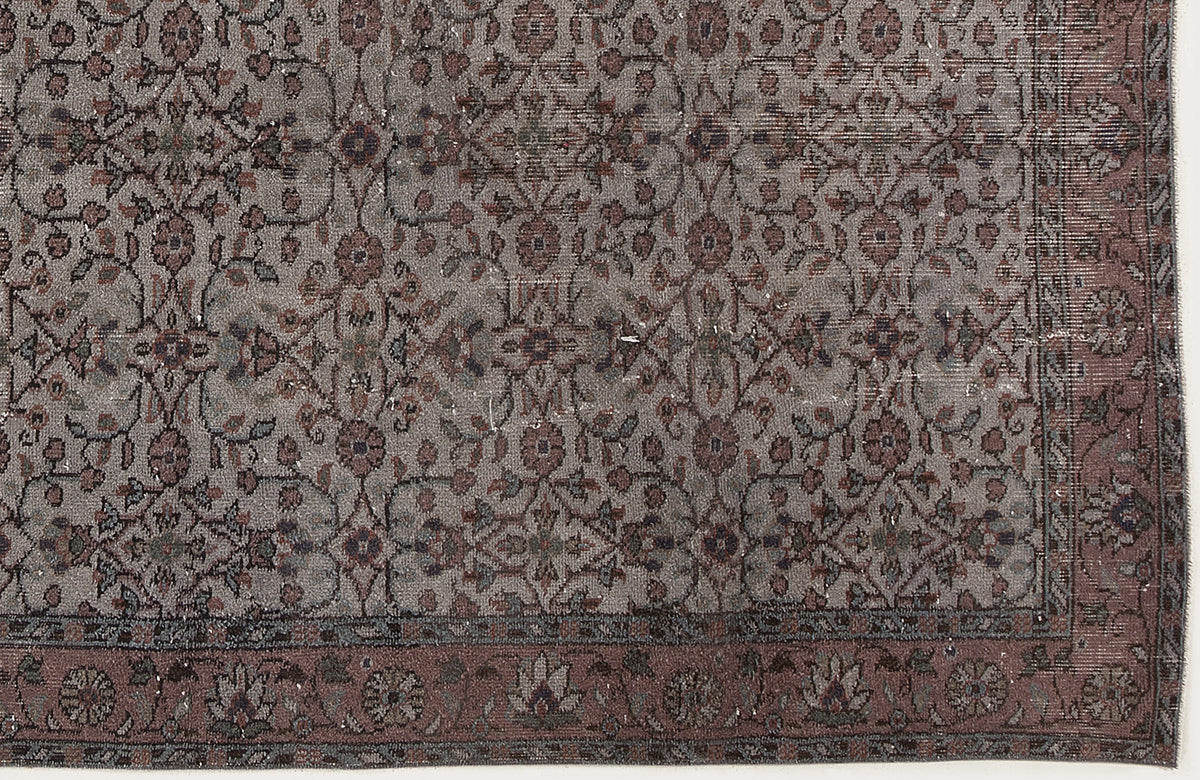 Grey and muted red traditional rug with a distressed floral vine pattern and a detailed border.