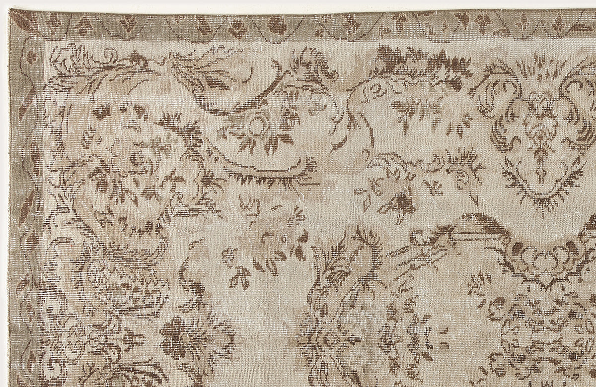 Beige and brown distressed rug with a traditional floral medallion pattern and a geometric border.