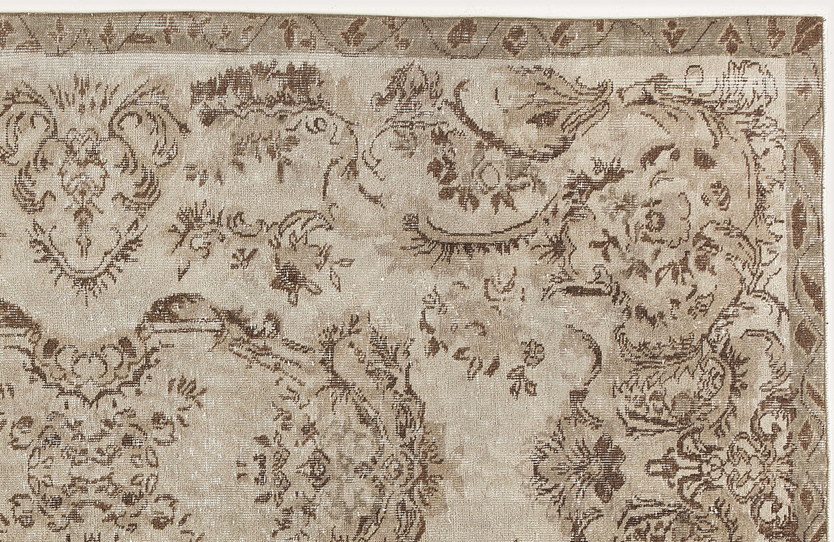 Beige and brown vintage-style rug with a distressed floral medallion pattern and a decorative border.