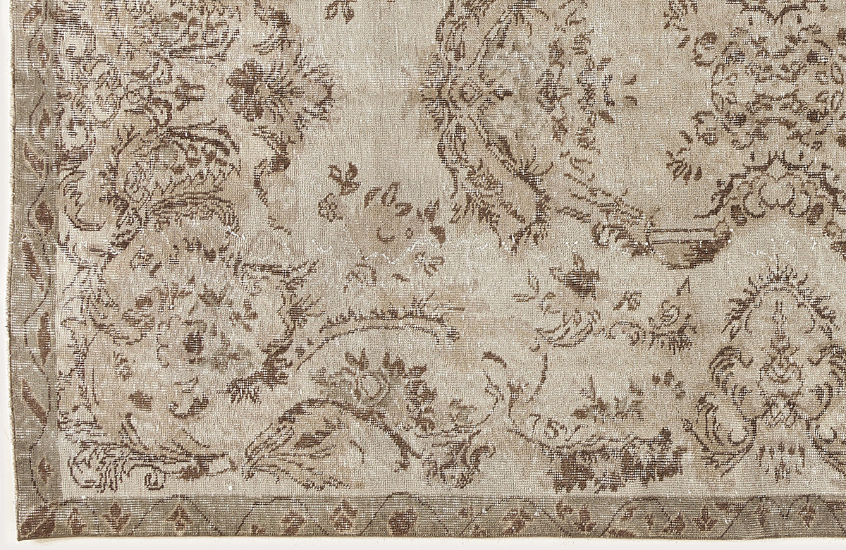 Beige and taupe vintage-style rug with a distressed floral medallion pattern and a geometric border.