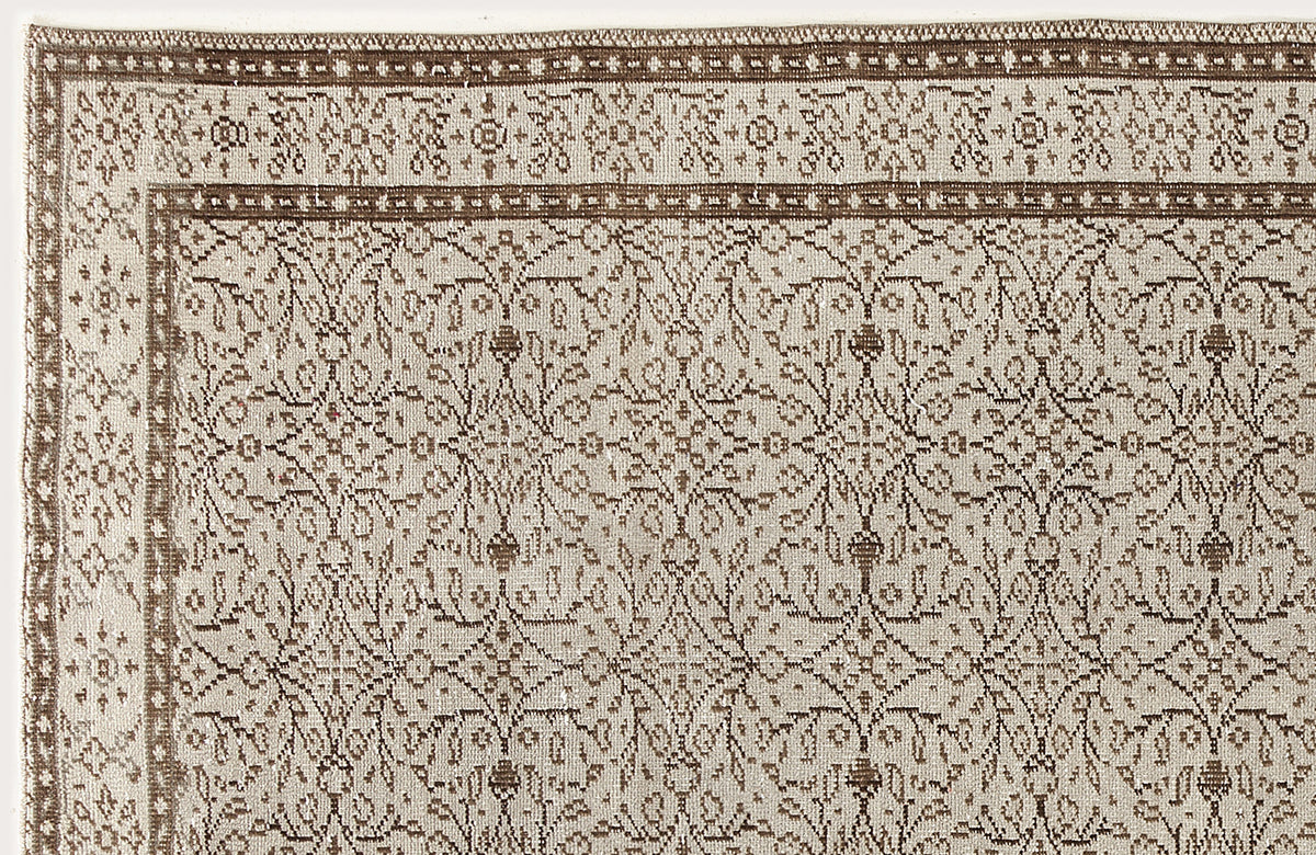 Beige and brown rug with a traditional floral medallion pattern and a detailed geometric border.