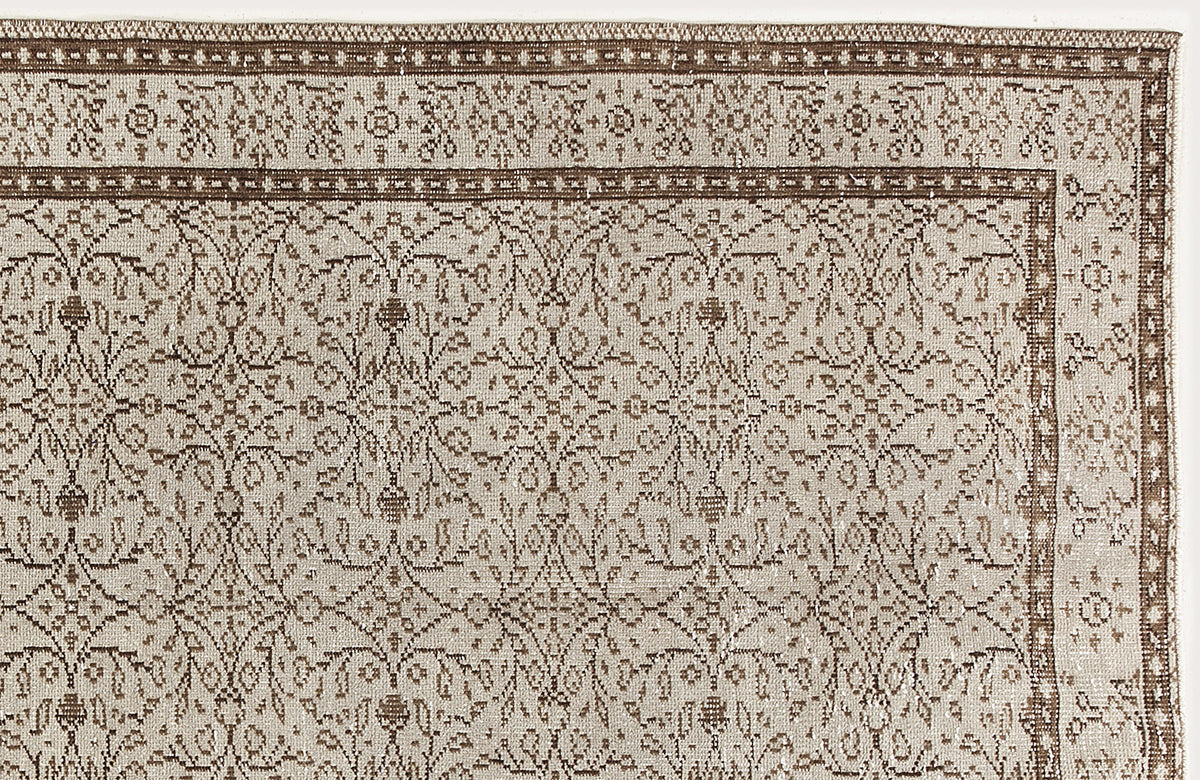 Beige and brown traditional rug with a repeating floral medallion pattern and a detailed geometric border.