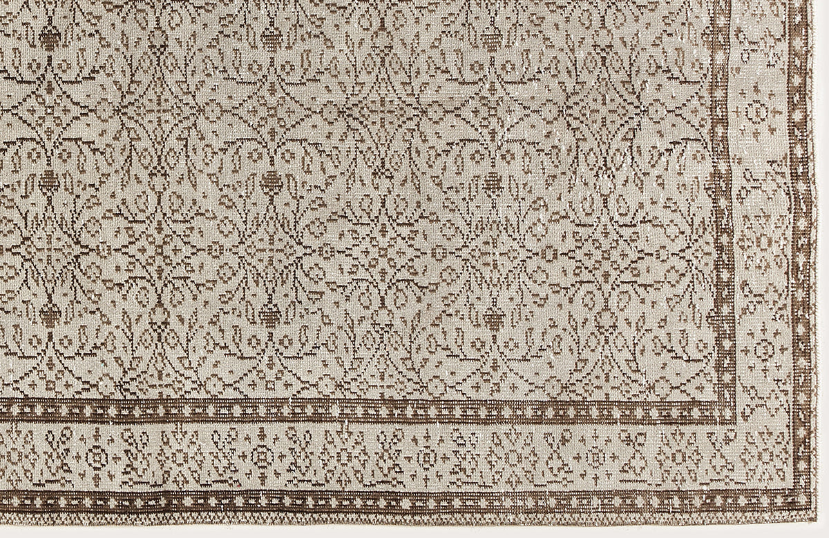 Beige and brown vintage-style rug with a repeating floral medallion pattern and a detailed geometric border.