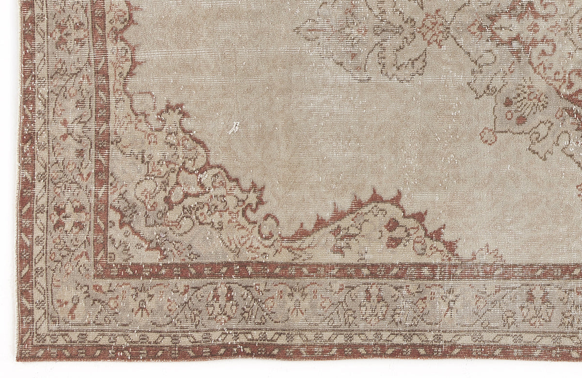 Beige and terracotta distressed rug with a traditional floral medallion border and faded vintage pattern.