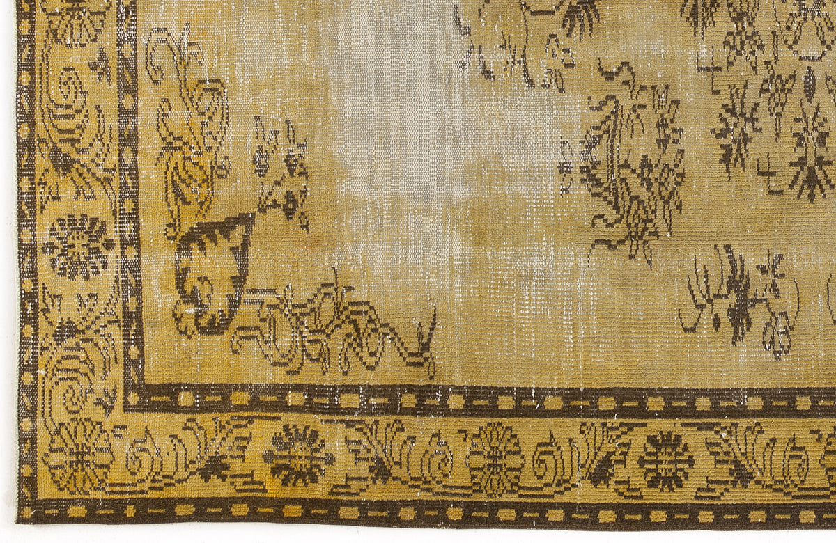 Distressed ochre and brown vintage-style rug with a faded floral medallion border and central motif.