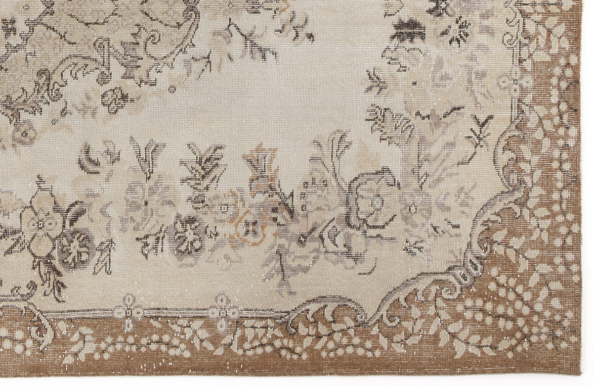 Beige and brown vintage-style rug with a distressed floral medallion pattern and a detailed border.