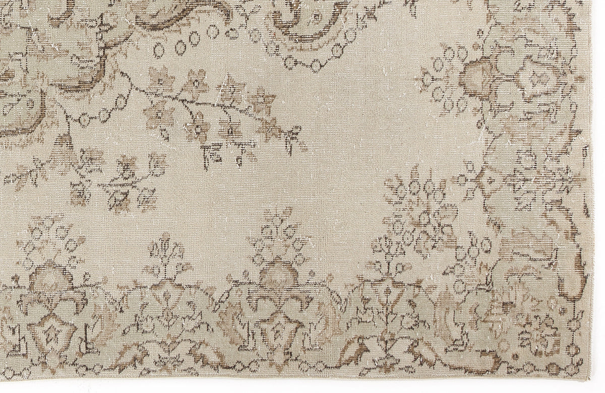 Beige and taupe distressed rug with a faded floral medallion and vine pattern.