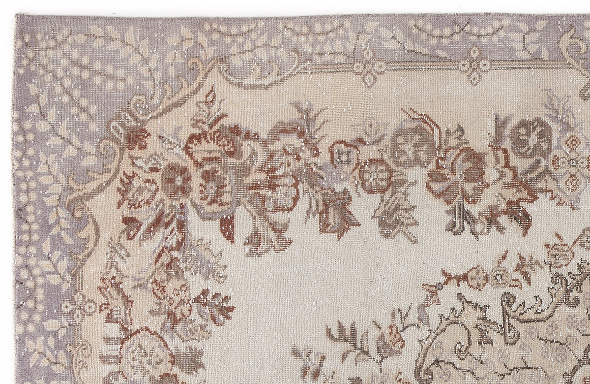 Distressed beige, lavender, and brown rug with a traditional floral border and medallion pattern.