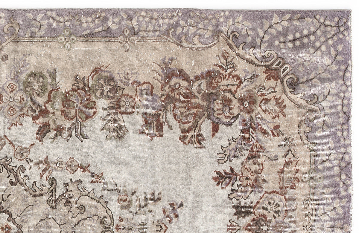 Beige and lavender traditional rug with a distressed floral medallion pattern and ornate border.