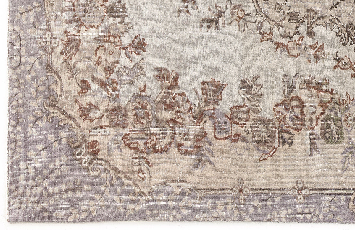 Beige and lavender vintage-style rug with a distressed floral medallion pattern and ornate border.