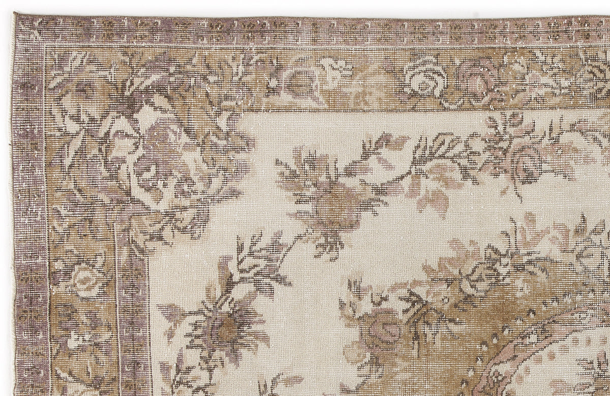 Distressed beige and mauve floral area rug with a traditional border pattern on a white background.