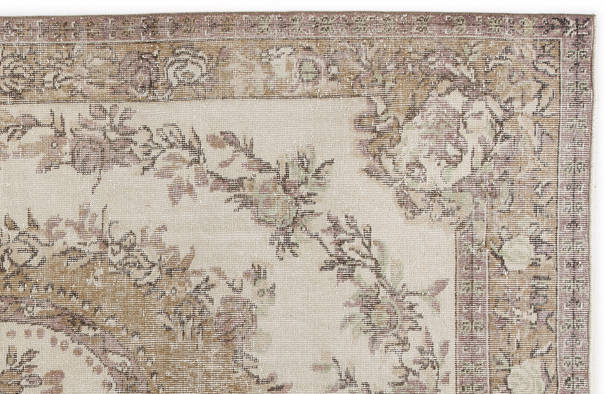 Distressed beige and mauve rug with a traditional floral medallion pattern and a detailed border.