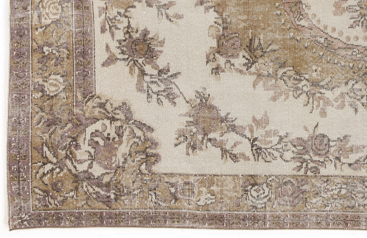 Beige and mauve vintage-style rug with a distressed floral medallion pattern and a decorative border.