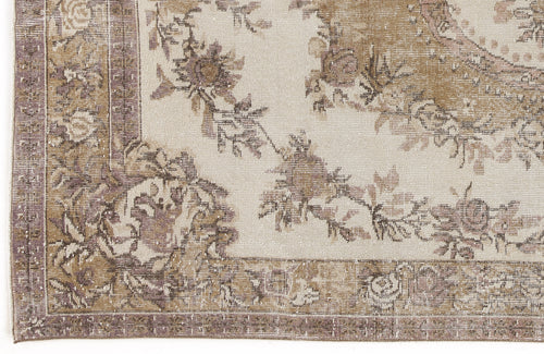 Load image 1 in gallery view. Beige and mauve vintage-style rug with a distressed floral medallion pattern and a decorative border.