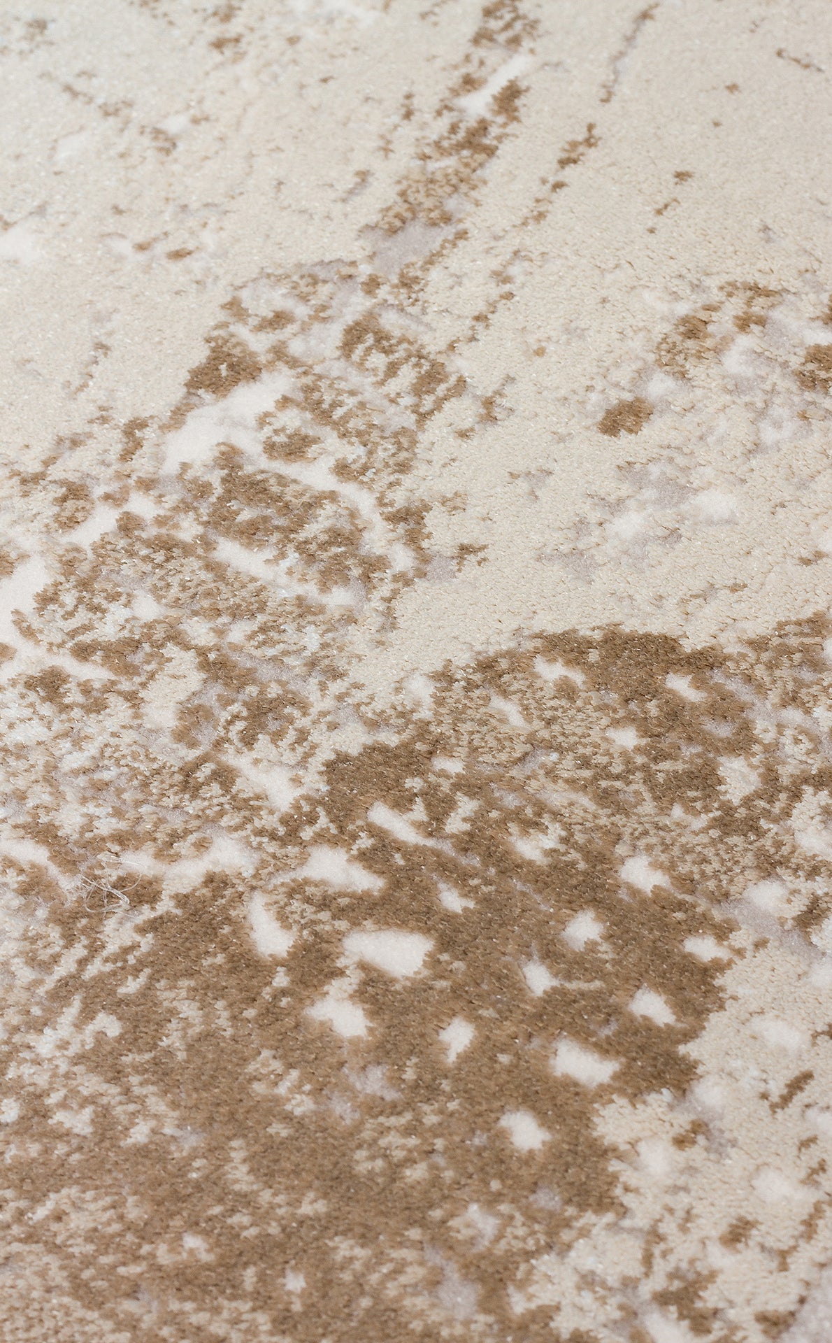 Close-up of a cream and taupe rug with a distressed, abstract mottled pattern.
