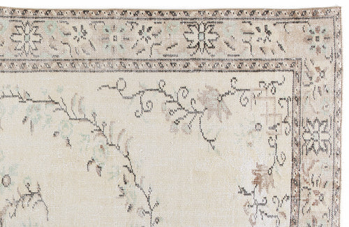 Load image 1 in gallery view. Beige rug with a distressed floral medallion border and faded vine motifs in muted brown and soft blue.