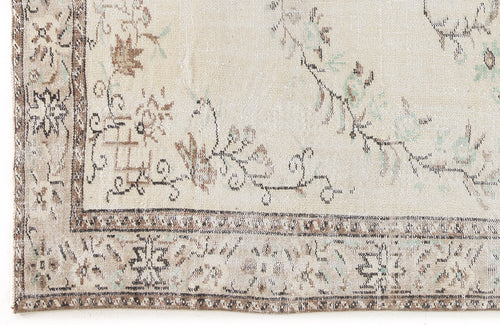 Load image 1 in gallery view. Cream rug with a distressed floral border and central vine pattern in muted brown, grey, and sage green.