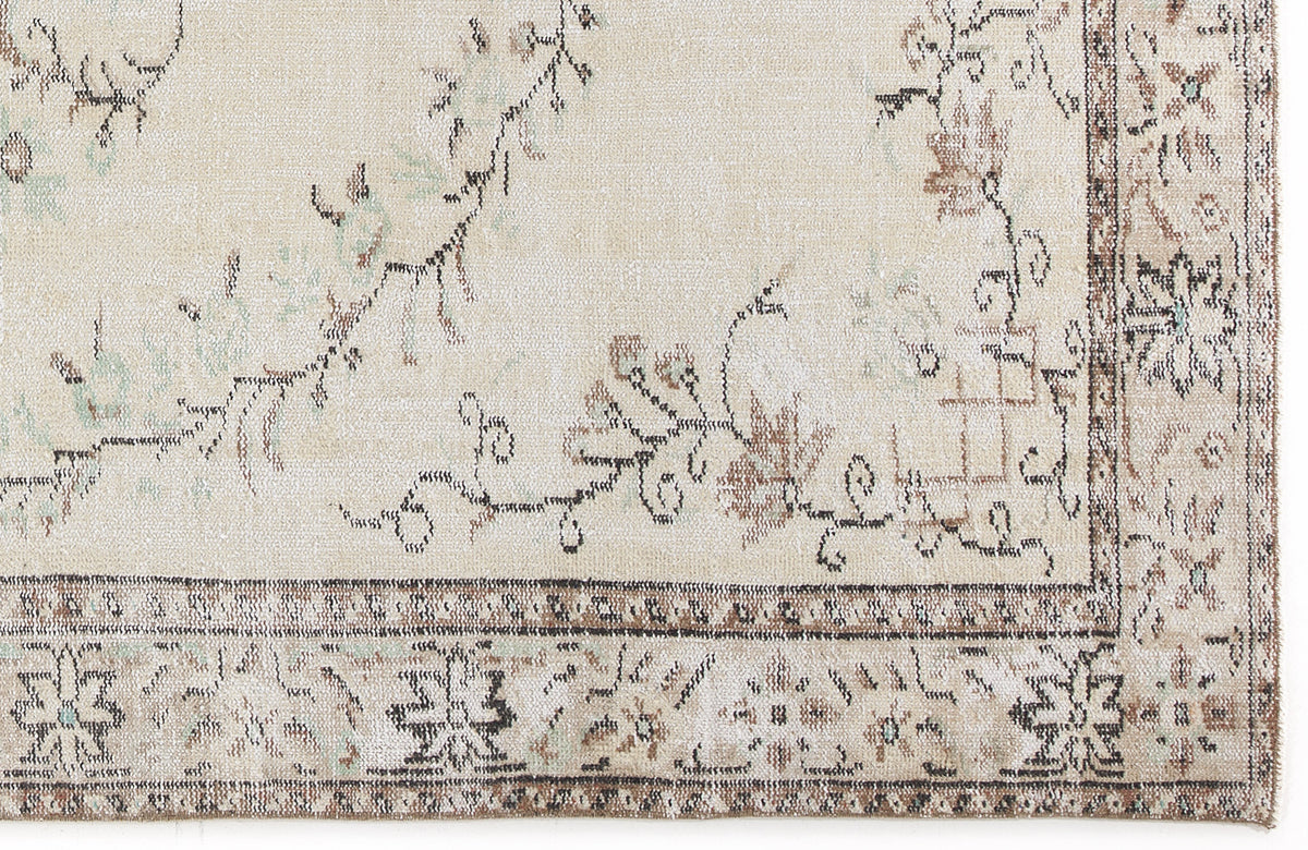 Beige rug with a distressed floral vine pattern and a dark brown geometric border.