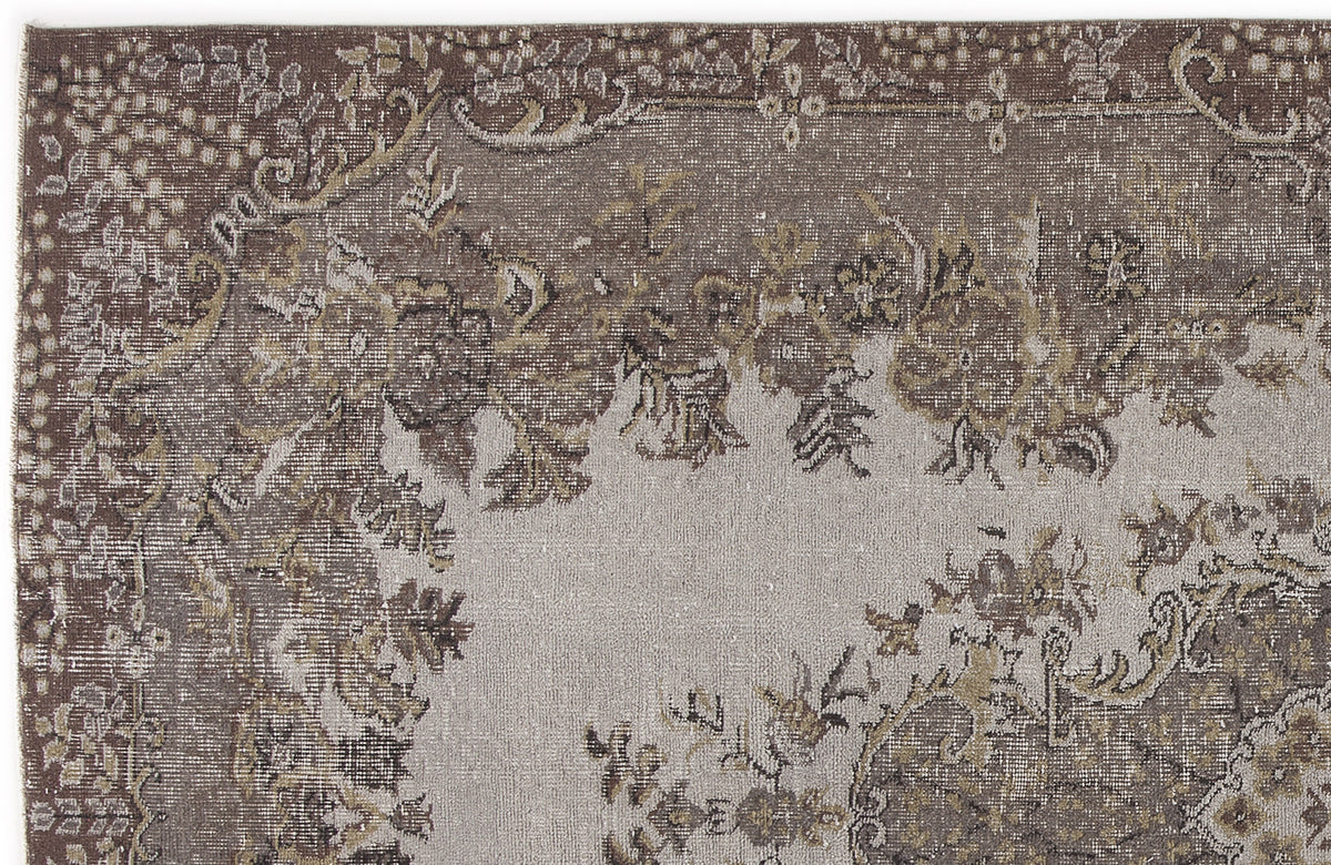 Brown and grey distressed rug with a traditional floral medallion pattern and ornate border.