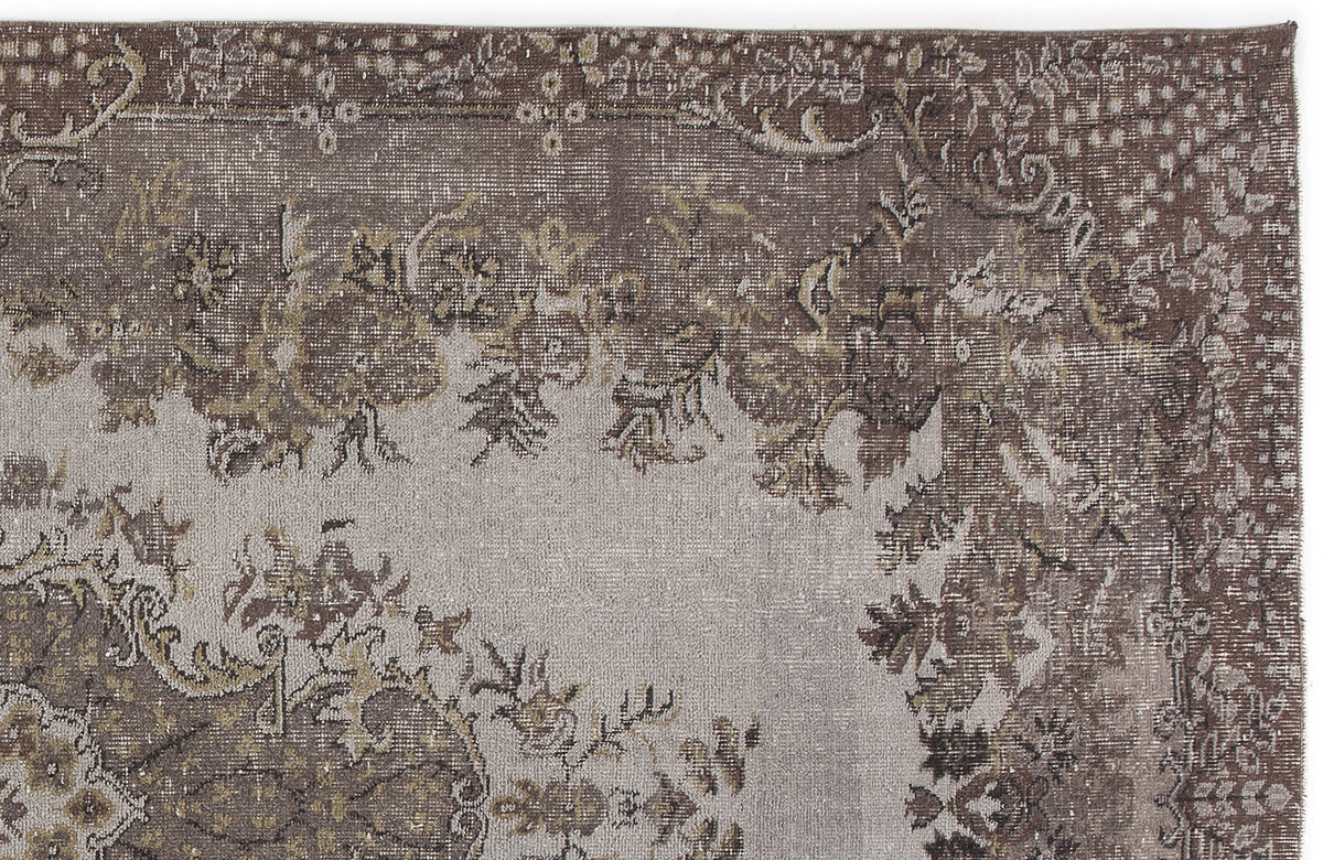Distressed brown and grey rug with a faded traditional floral medallion pattern on a white background.