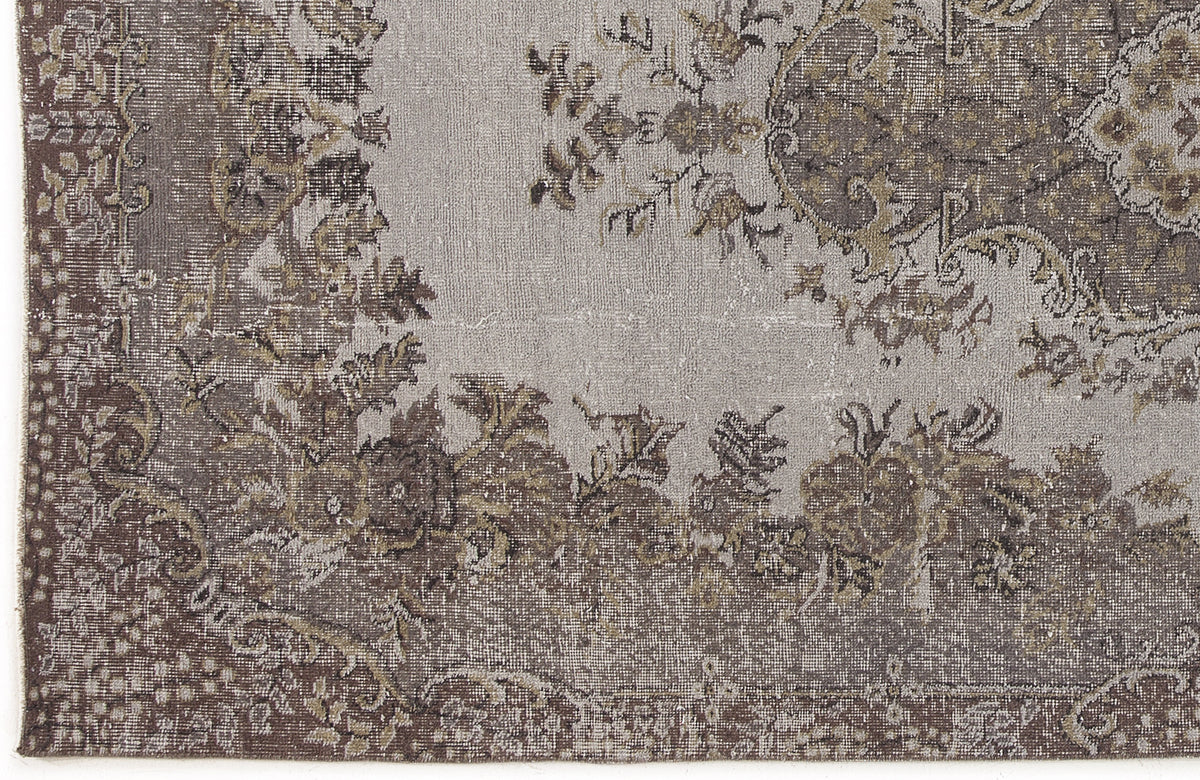 Grey and brown distressed rug with a traditional floral medallion pattern and ornate border.