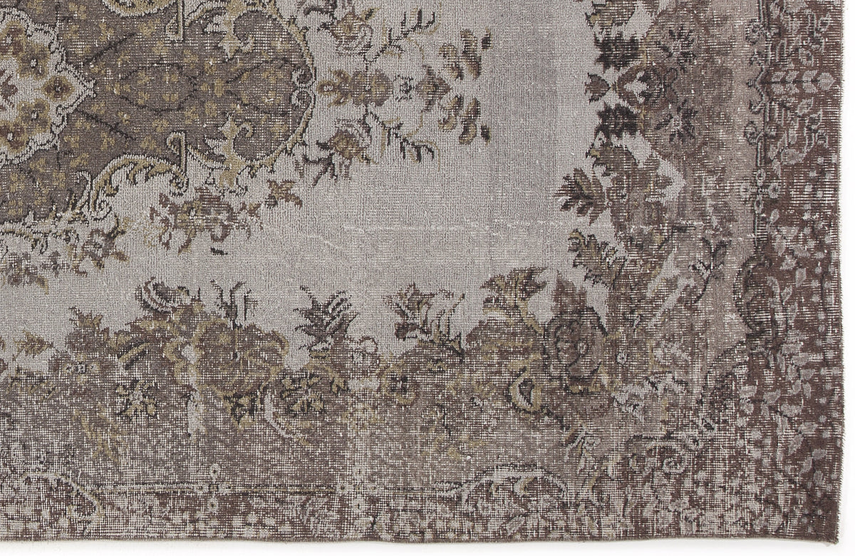 Grey and brown distressed rug with a traditional floral medallion pattern and ornate border.