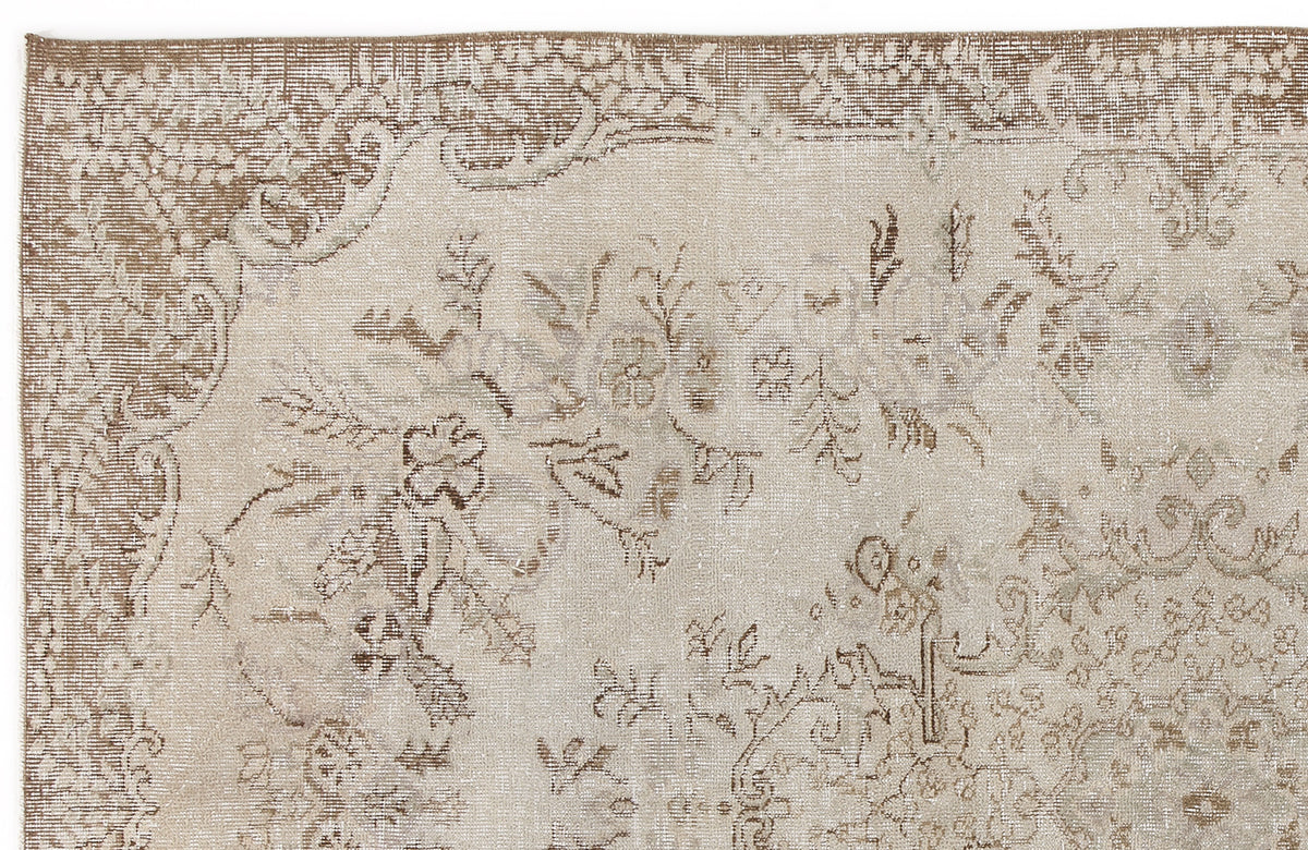 Beige and taupe distressed rug with a faded floral medallion pattern.